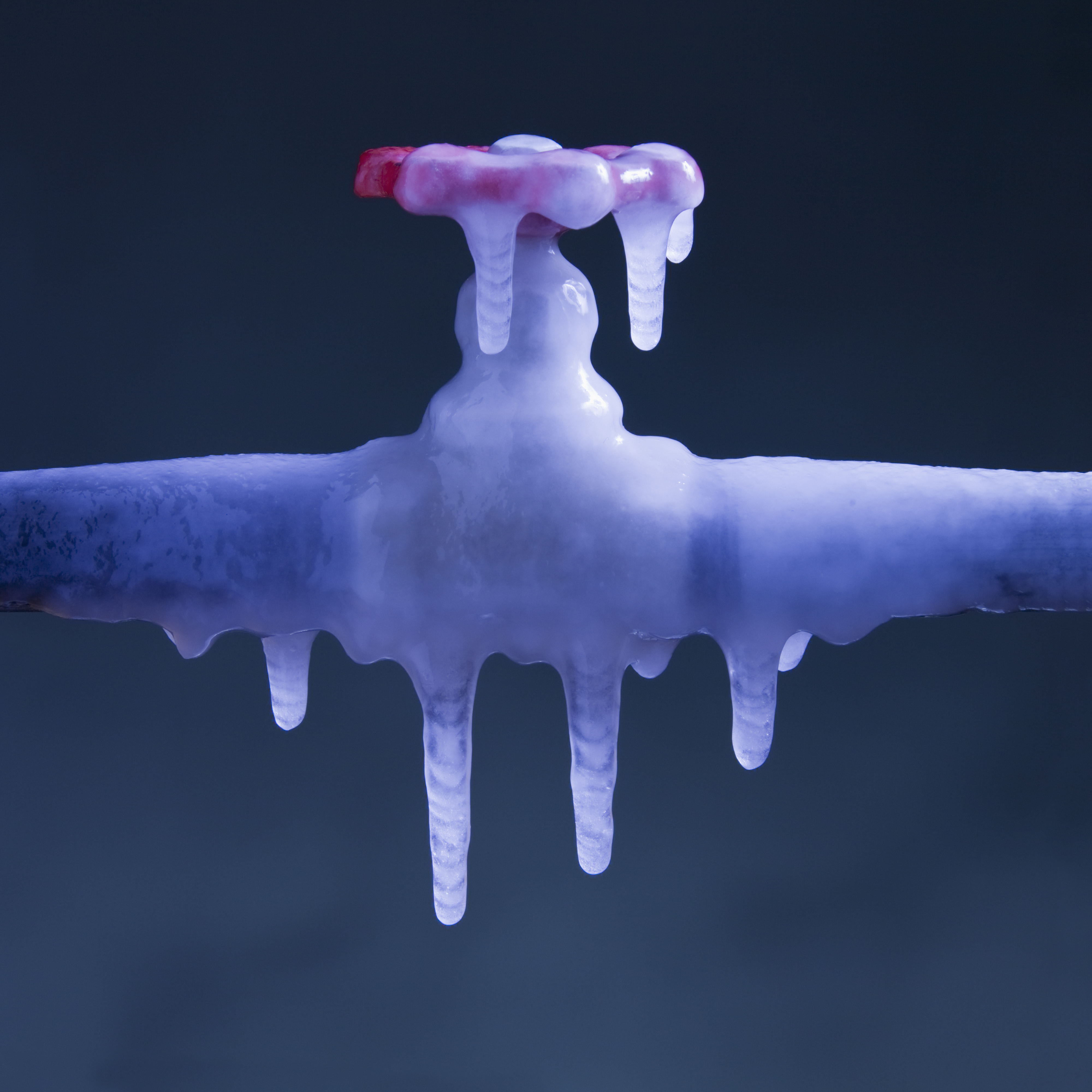 A frozen faucet with icicles hanging, depicting extreme cold affecting plumbing