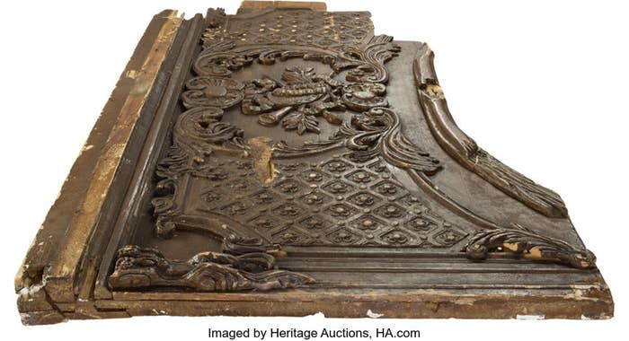 Ornate carved wooden panel, possibly an antique or art piece, with visible wear