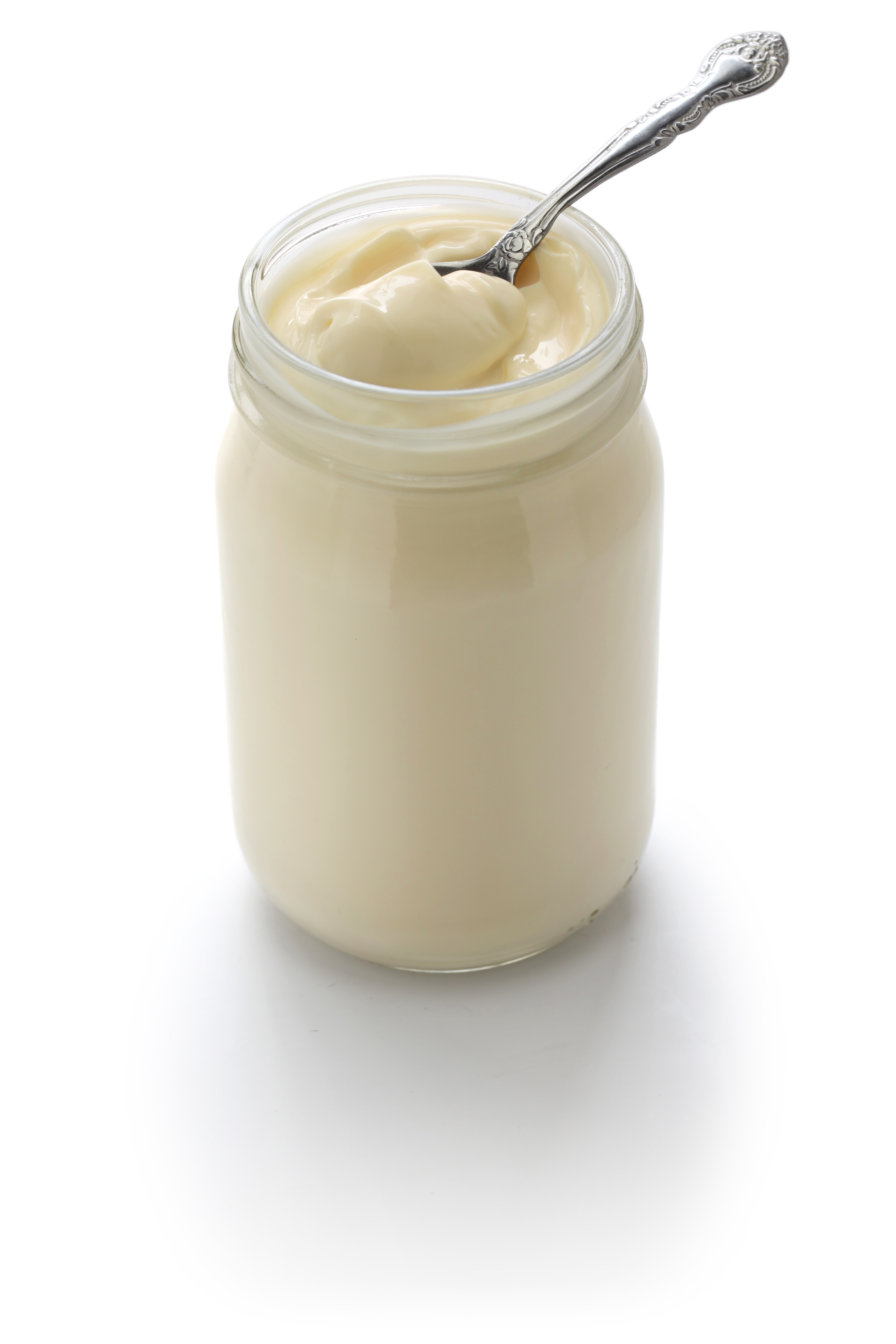Jar of mayonnaise with a spoon inside on a white background