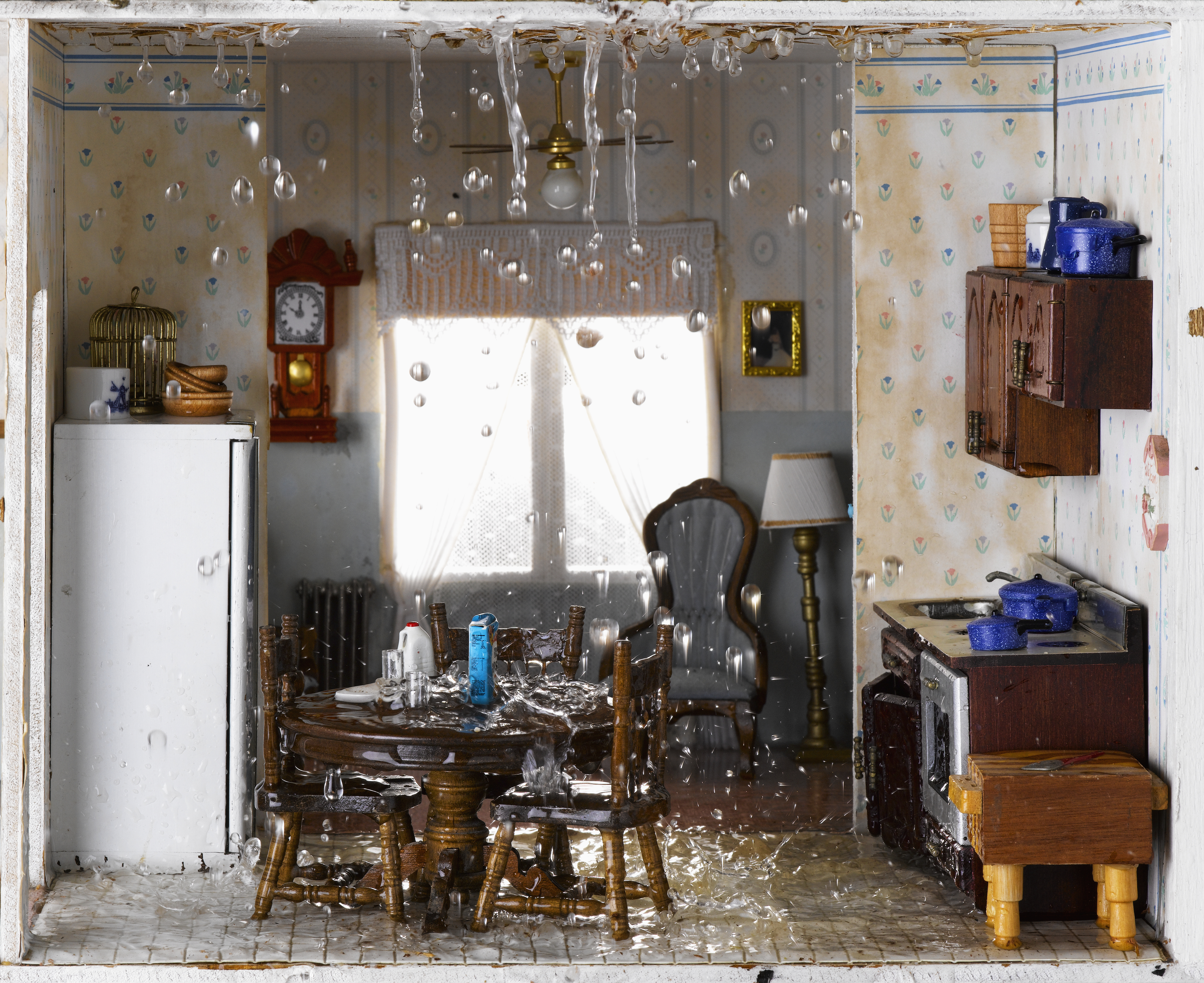 Miniature model of a flooded kitchen with floating debris, illustrating potential home damage