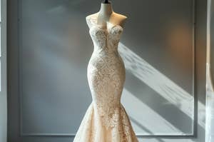 A mannequin displaying an intricate lace wedding dress with a mermaid silhouette