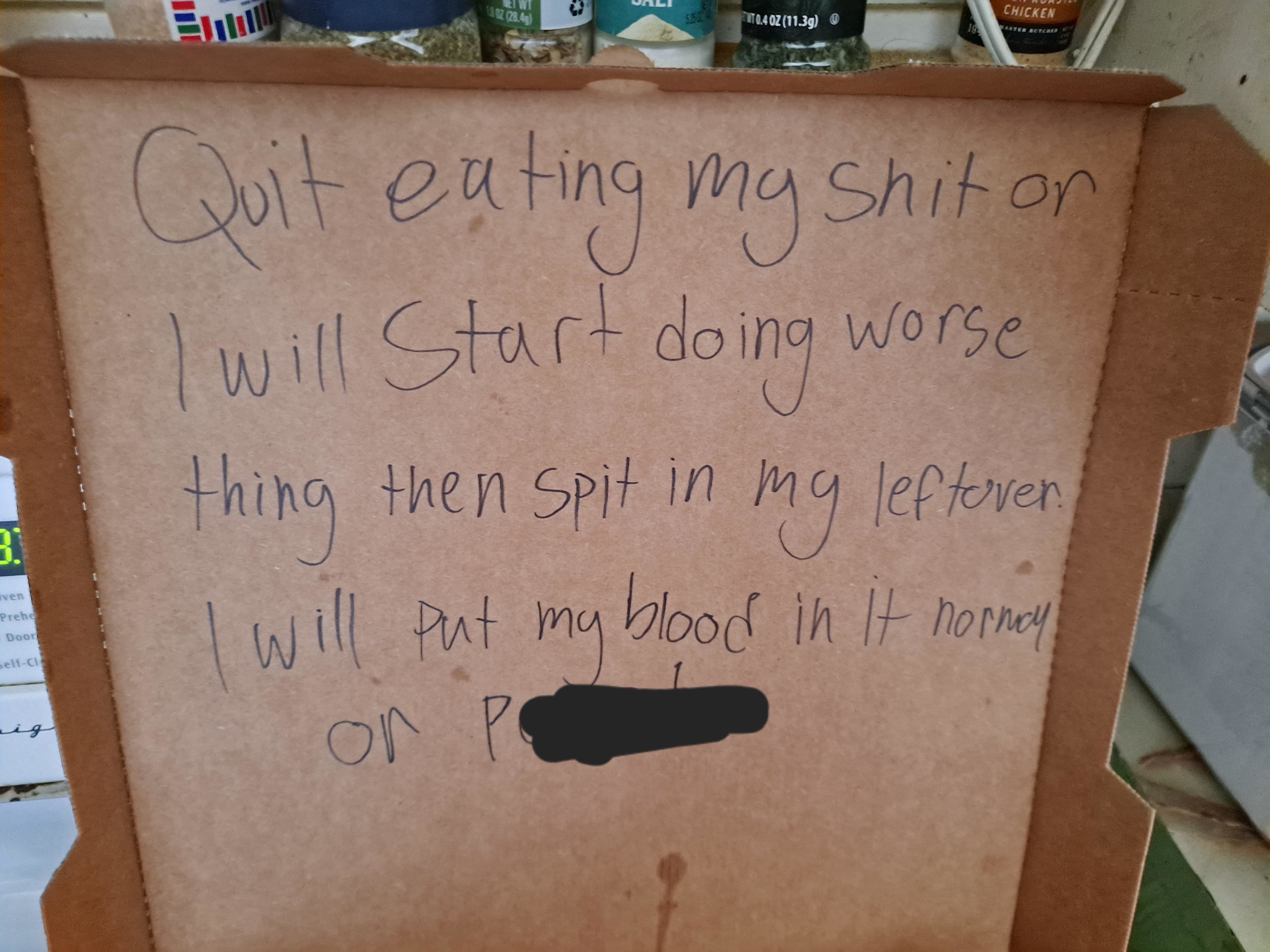 Handwritten note on cardboard with a threatening message about tampering with food