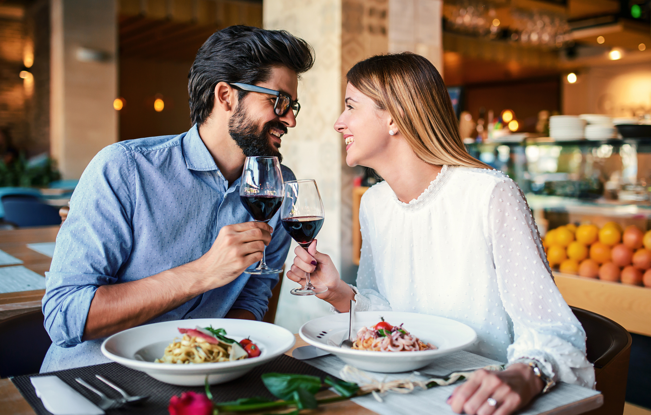 Two people enjoying a meal and toasting with wine glasses at a restaurant