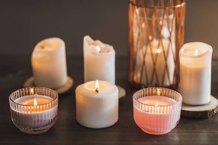 A variety of lit and unlit candles on a surface, some in holders, creating a cozy ambiance