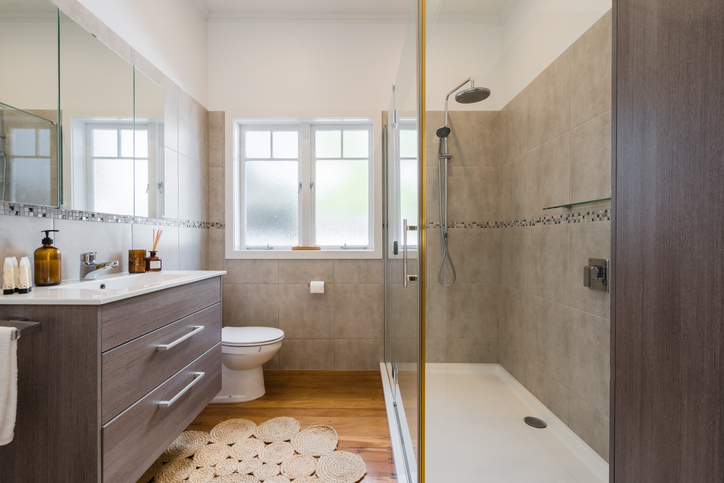 Modern bathroom with a walk-in shower, toilet, and vanity. There&#x27;s a frosted window and tiled walls