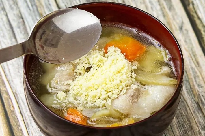 スプーンで提供されるコップに入った野菜と肉のスープ。