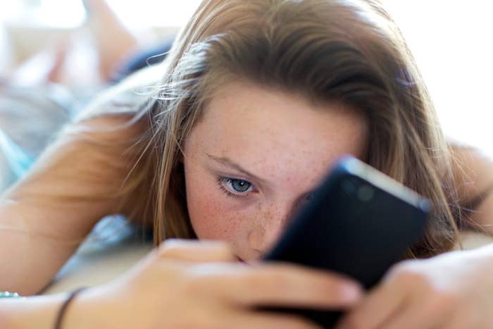 A person lying down while intently looking at a smartphone screen
