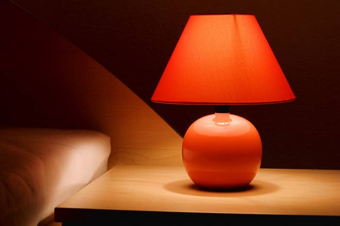 Illuminated table lamp on a nightstand creating a warm ambiance in a dimly lit room