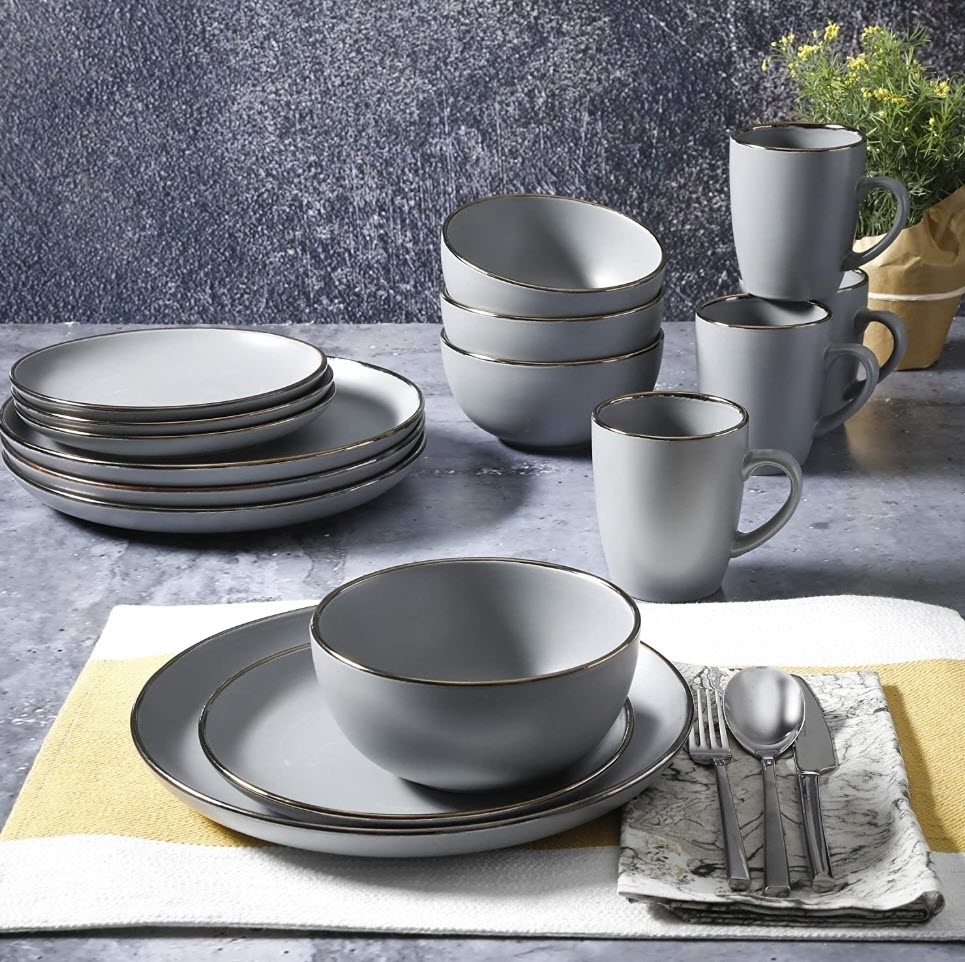 A set of gray dinnerware including plates, bowls, and mugs, arranged on a table