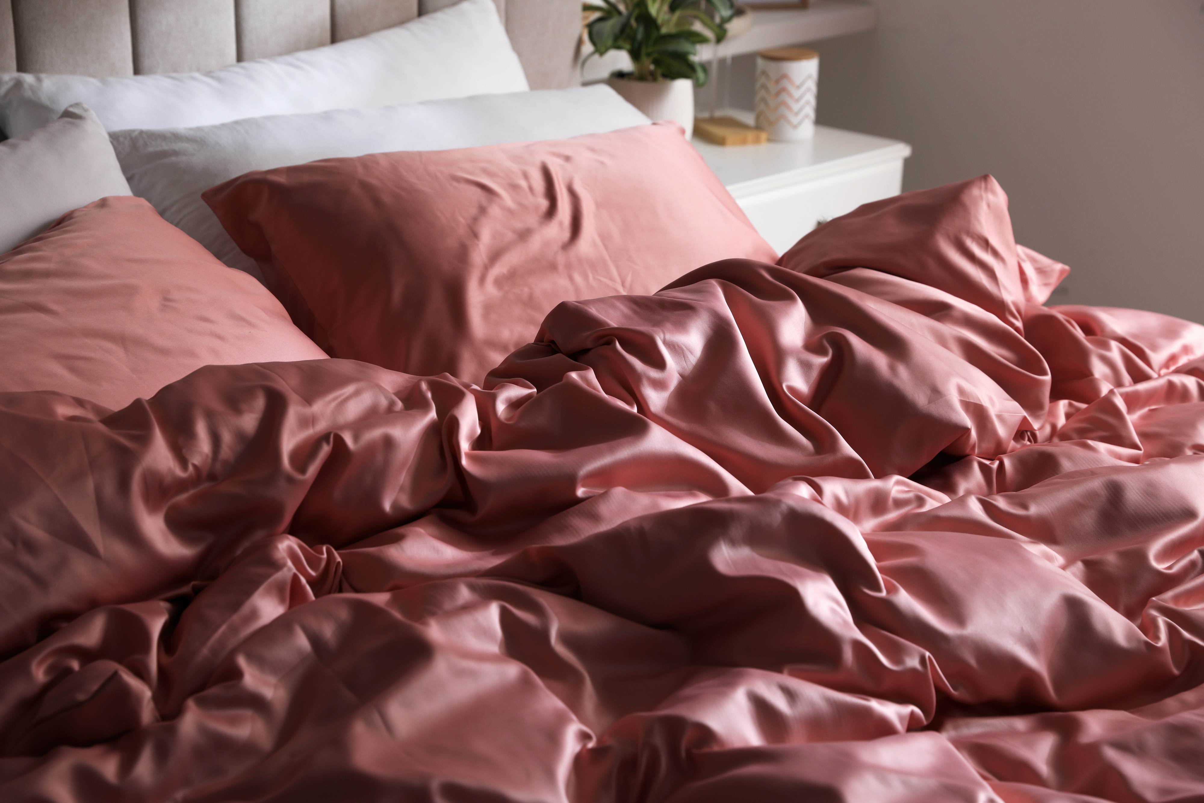 Unmade bed with rumpled pink sheets and pillows, suggesting recent use or lack of tidiness