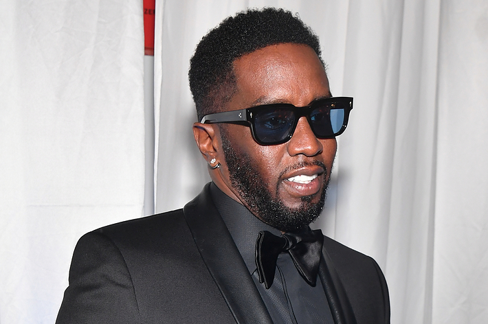 Music artist in a black tuxedo and sunglasses poses for a photo