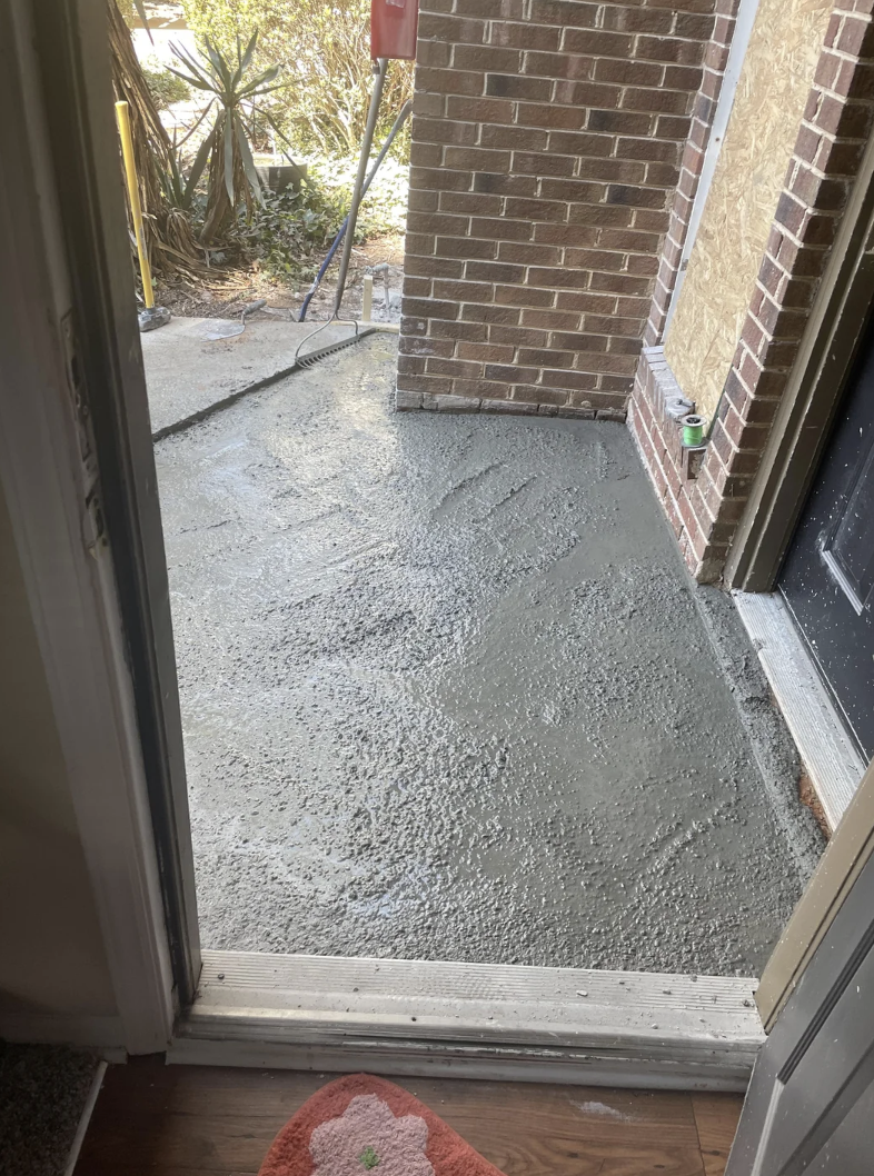 Freshly poured wet concrete on a residential walkway viewed from an open door