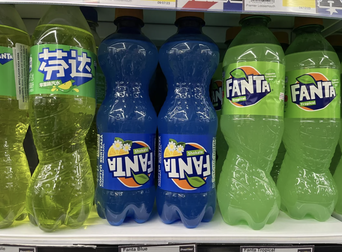 Bottles of Fanta in various flavors, including blue and tropical, on a store shelf
