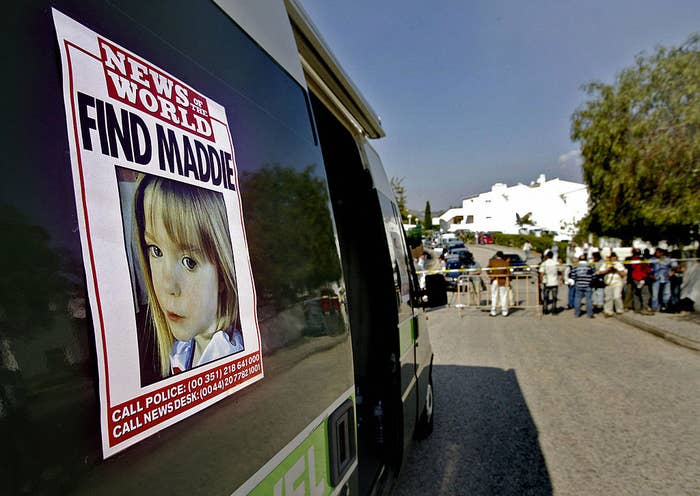 News of the World poster on a vehicle with &quot;FIND MADDIE&quot; headline, a crowd in the background