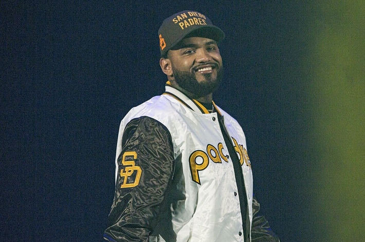 Man in a Padres baseball jersey and cap smiling on stage