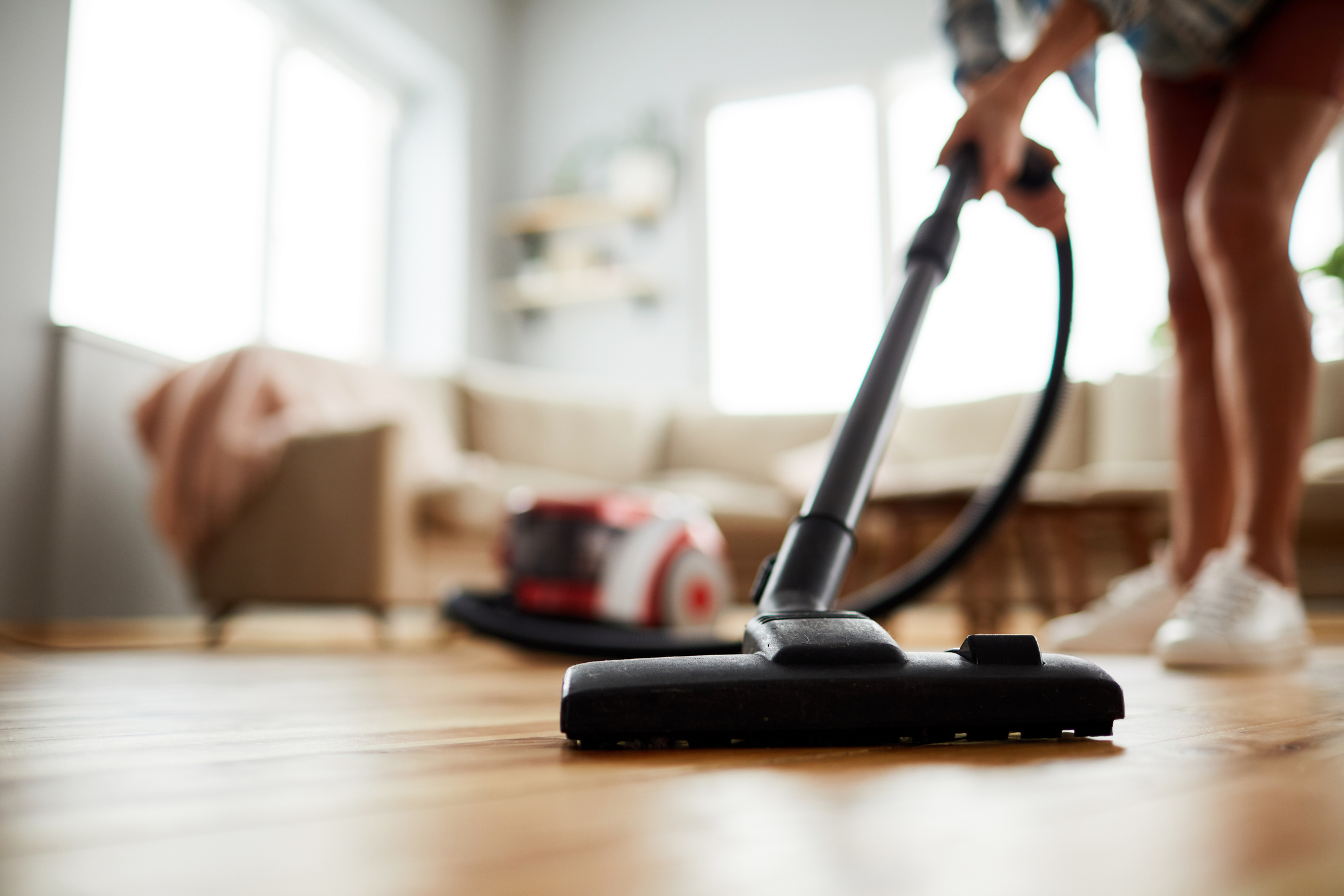 Person using a vacuum cleaner on a wooden floor in a living room