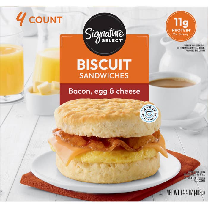 Advertisement showing Signature Select&#x27;s bacon, egg, and cheese biscuit sandwiches with a glass of orange juice and coffee mug in the background