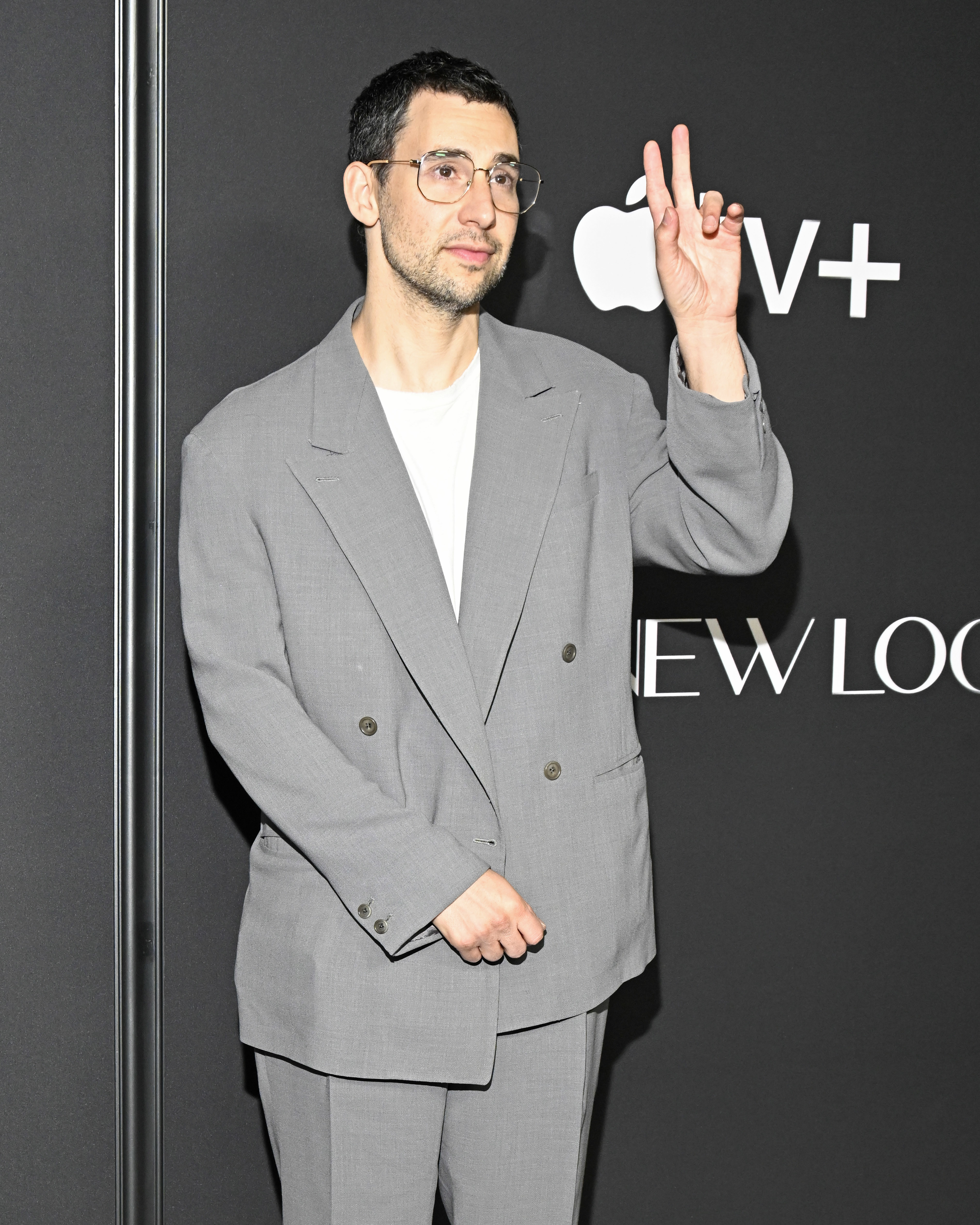 jack throwing up a peace sign while at an event dressed in a suit