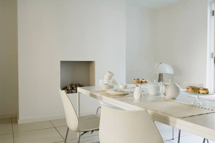 Modern minimalist kitchen with a sleek table set for tea, featuring a lamp and a fireplace