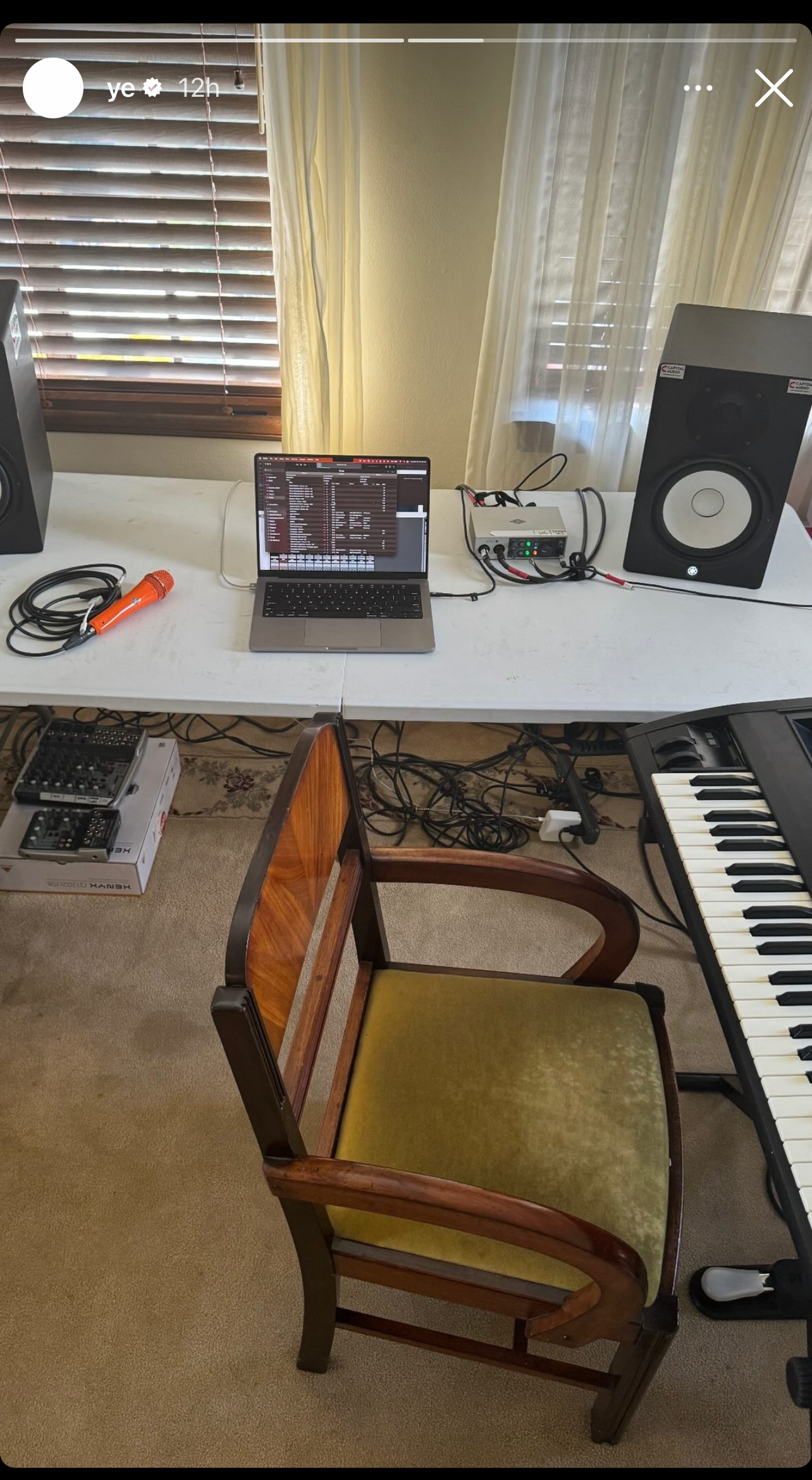 Home music production setup with laptop, audio interface, and studio monitor near a keyboard and chair