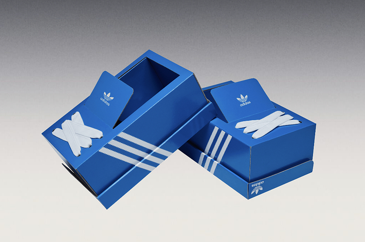 Two Adidas sneaker boxes with one open and displaying a white sneaker's silhouette
