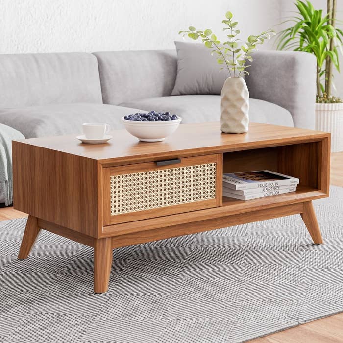Wooden coffee table with a storage section and a plant on top, suitable for a living room space