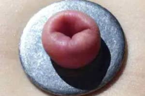 Close-up of a person puckering lips through a shiny ring, resembling a fish face