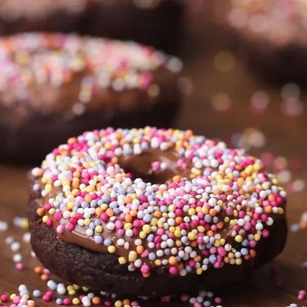 Chocolate donut topped with sprinkles on a wood surface