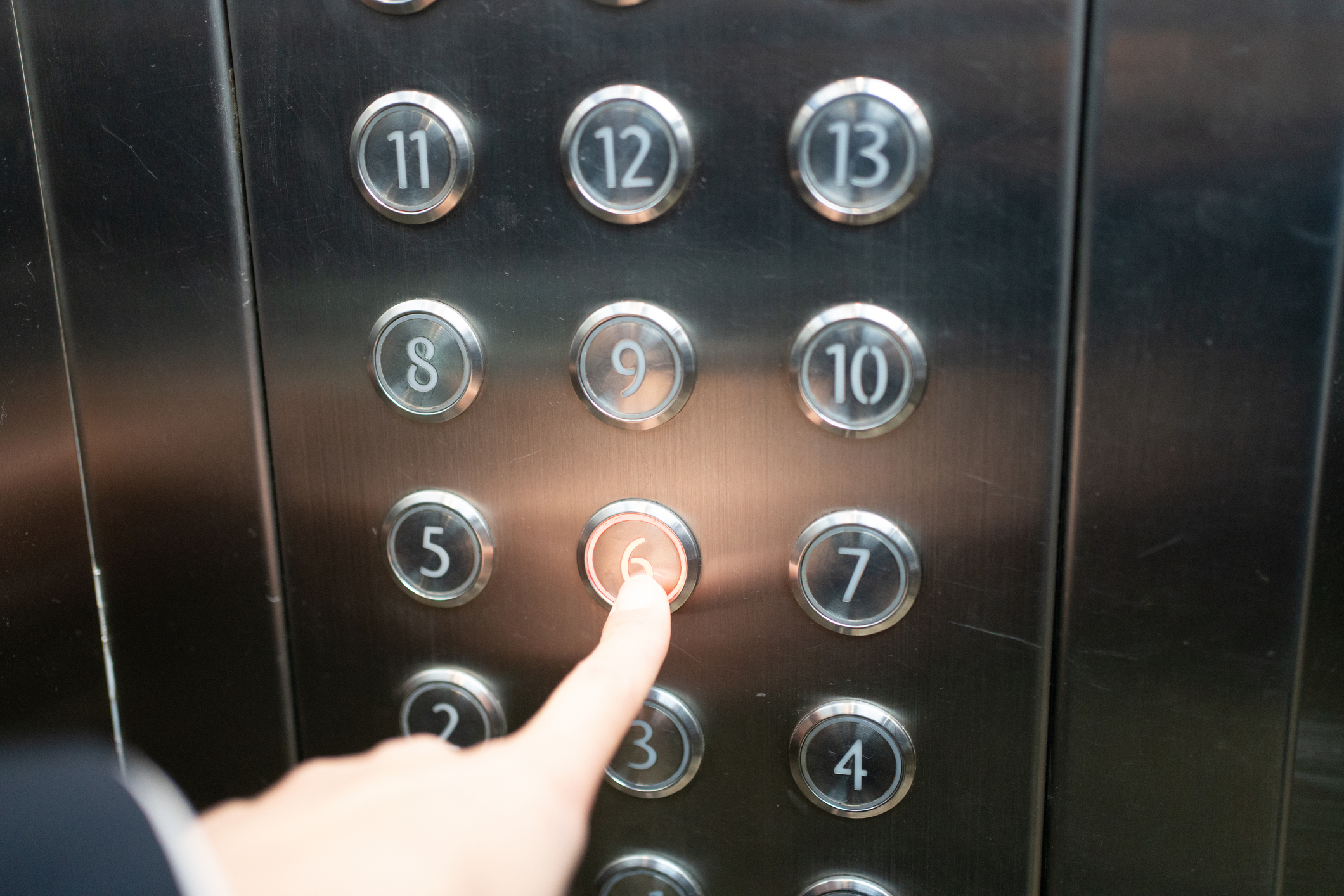Finger pressing an elevator button, implying travel between floors in a building