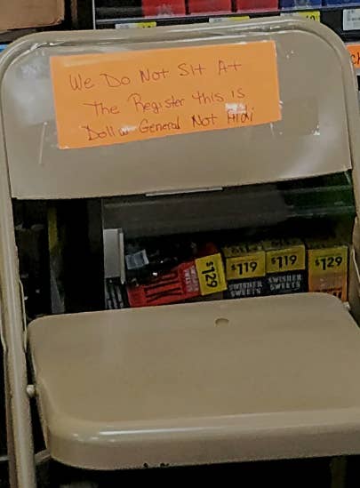 Handwritten sign on a chair stating &#x27;We Do Not Sit At The Register This Is Dollar General Not Aldi&#x27; indicating seating not allowed