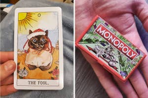 Person holding a tarot card featuring a cat as the fool; a hand holding a mini Monopoly game box