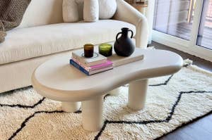 Modern living room with a stylish curved coffee table adorned with books and decorative items