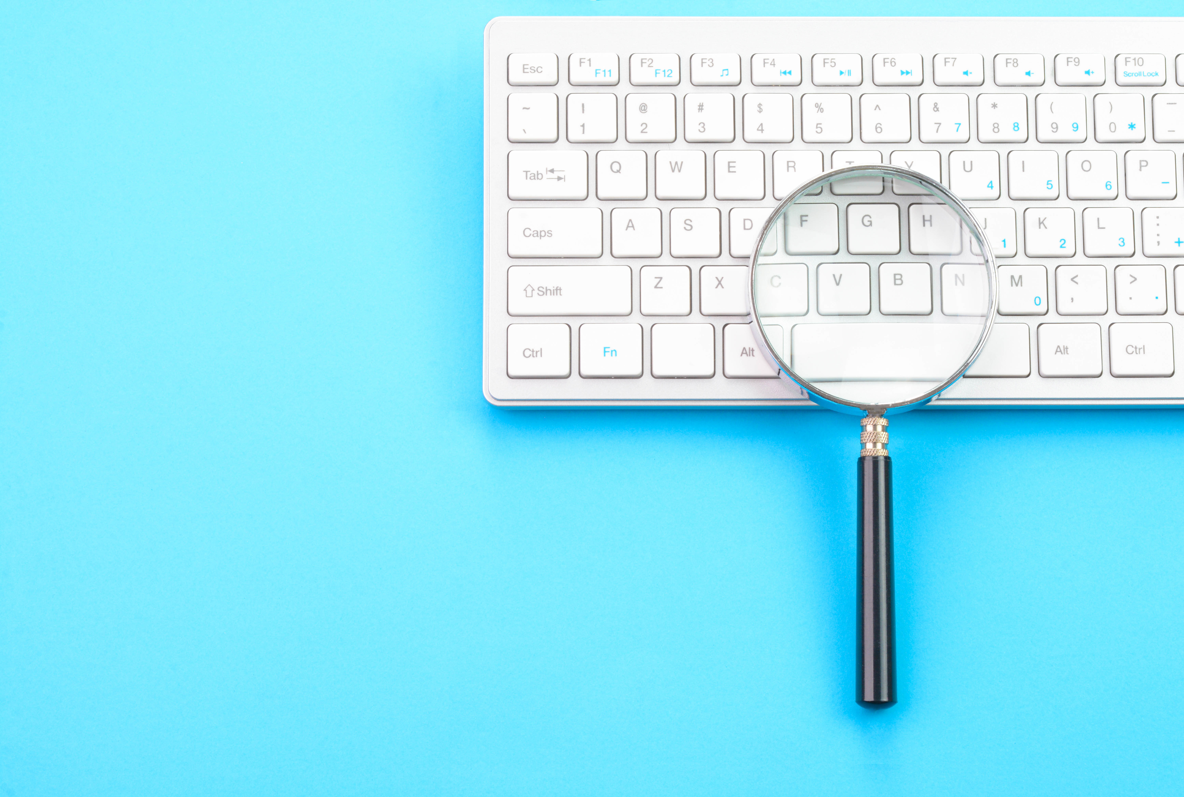 Magnifying glass over a keyboard, symbolizing job search