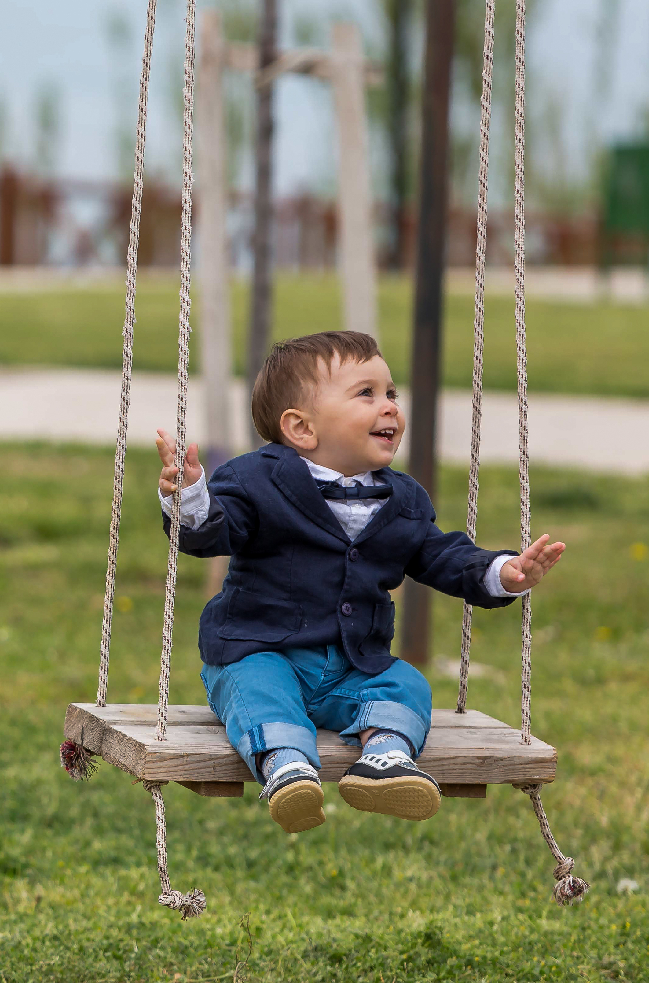 Toddler in a suit on a swing, looking happy