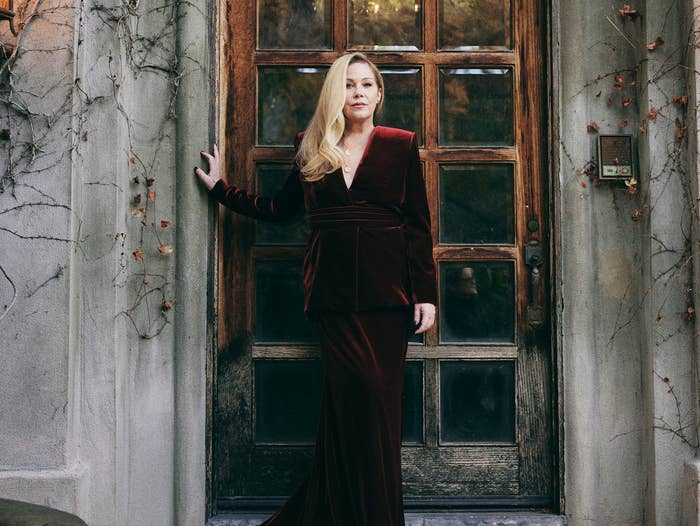 christina in an velvet dress standing at an old doorway with lanterns on either side