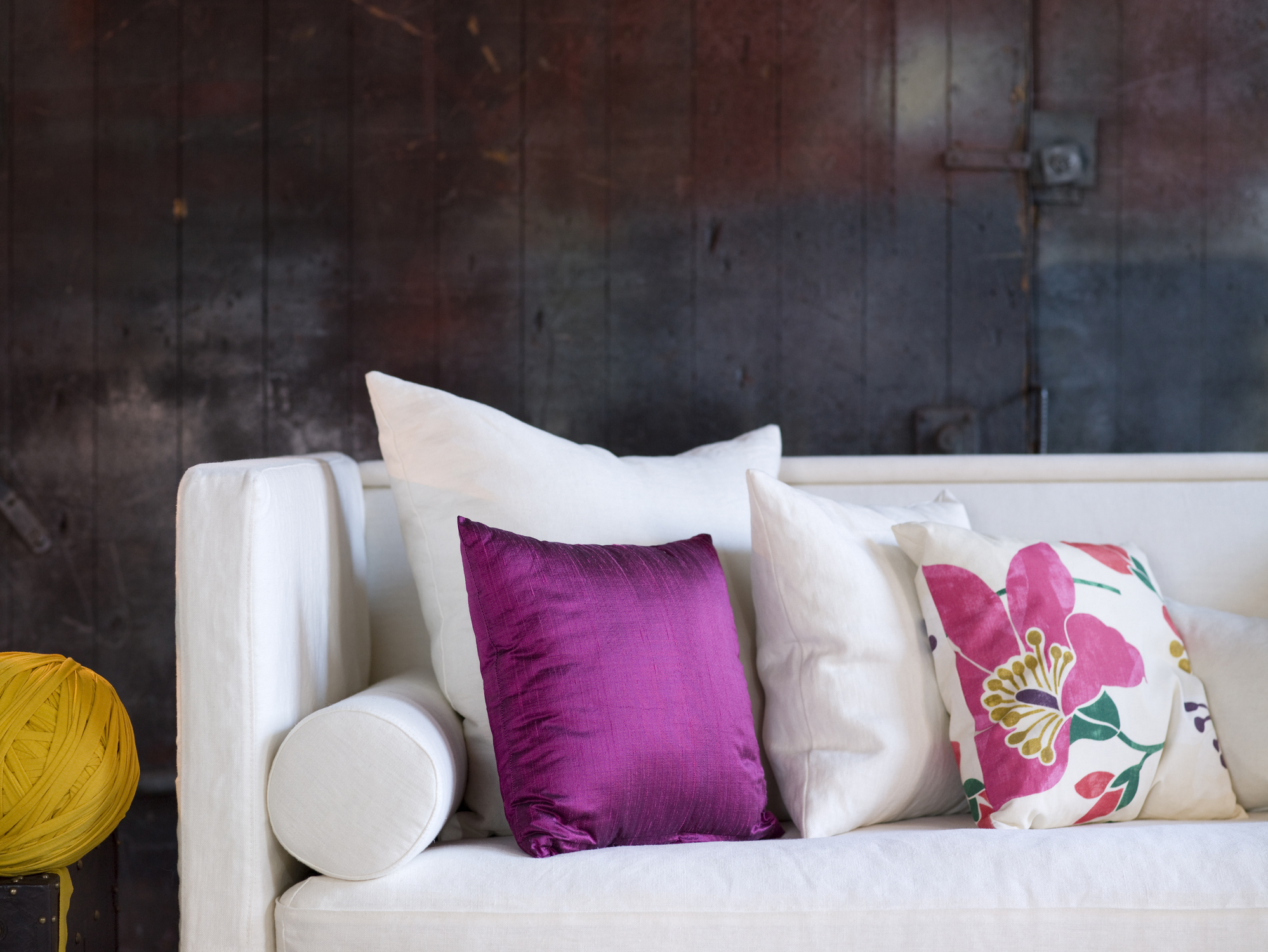 A white couch with mixed-style pillows against a distressed multicolored backdrop