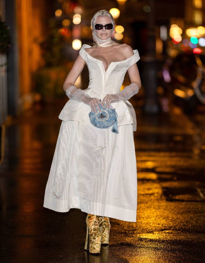 julia in an ankle-length couture dress and patterned boots poses on a city street at night