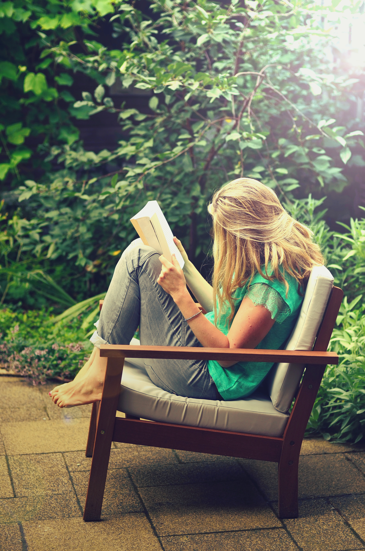 Woman reading a book in a garden chair, relaxing outside