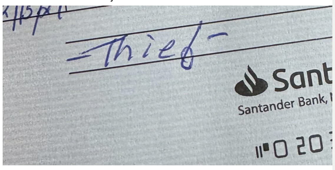The image shows a close-up of a check with &quot;Thief&quot; written on the memo line, implying a dispute over owed compensation