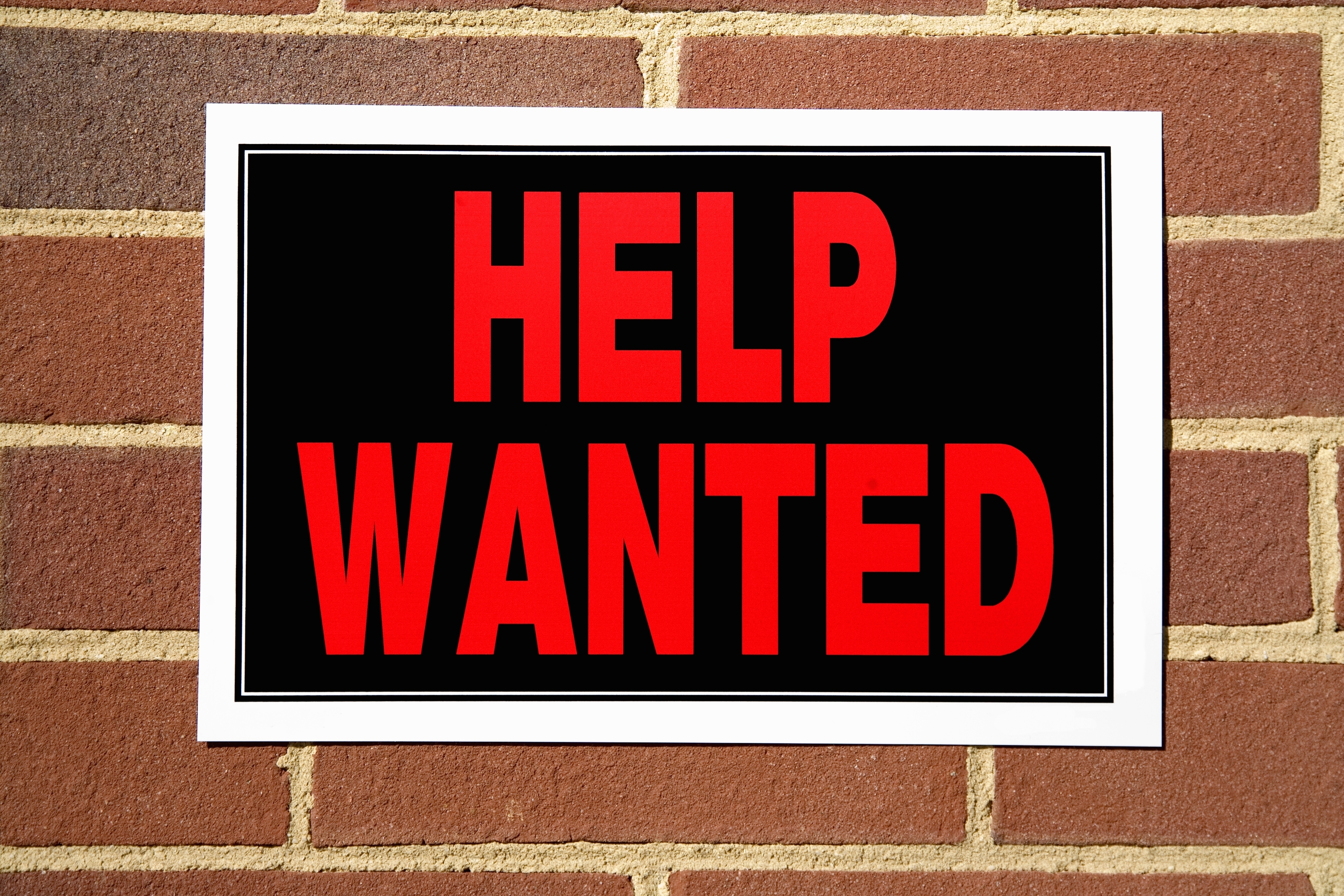 A &quot;Help Wanted&quot; sign on a brick wall