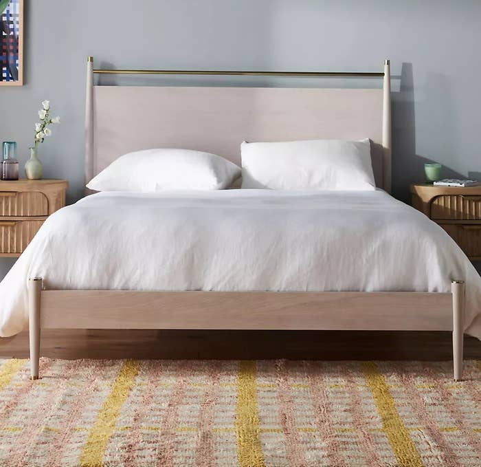 Modern minimalist wooden bed frame and bedside table with bedding, in a clean bedroom setup for shopping context