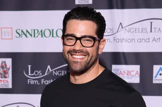 Jesse Metcalfe posing in a black t-shirt and beige trousers at an event