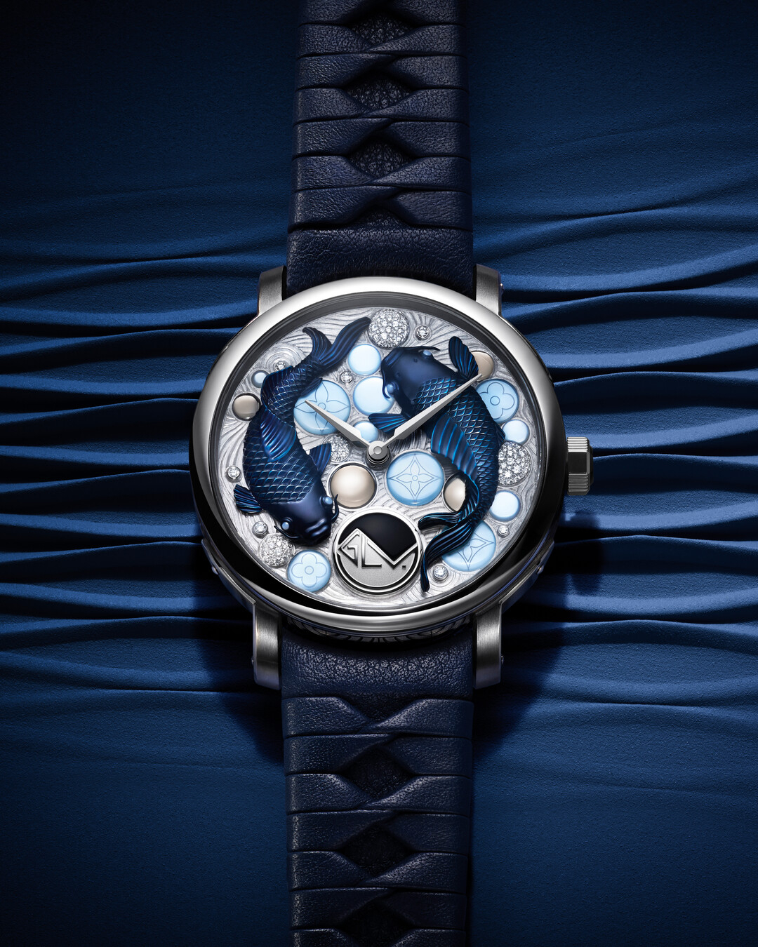 Luxury watch with intricate fish design on face, encased in silver on a textured blue strap