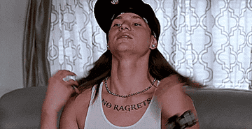 Person with "NO RAGRETS" tattoo adjusts their shirt collar