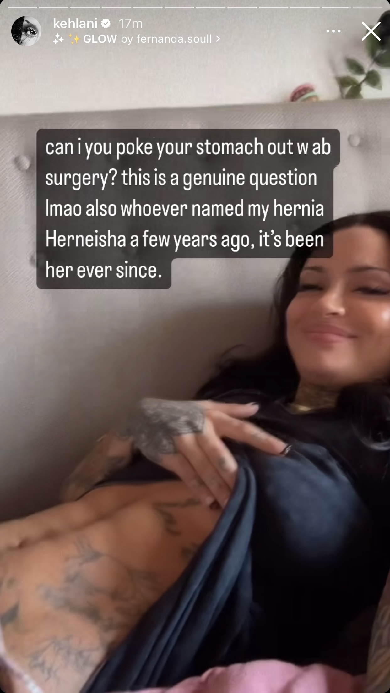 Smiling Kehlani lounging, with tattooed arm resting on torso and caption: &quot;can i poke your stomach out w ab surgery? this is a genuine question lmao also whoever named my hernia Herneisha a few years ago, it&#x27;s been her ever since&quot;