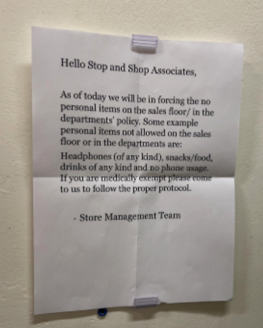 Notice on wall about store policy prohibiting personal items, food, drinks, and headphone use on the sales floor
