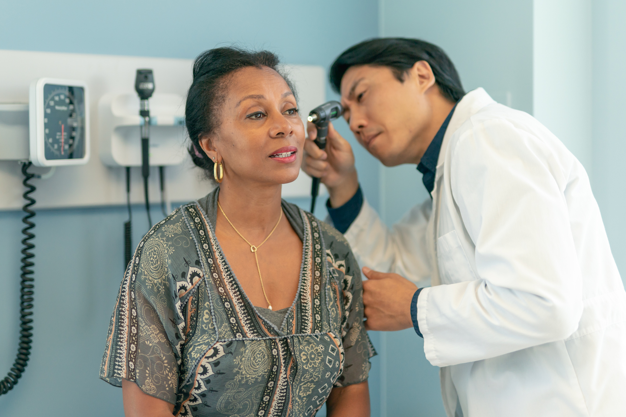 Doctor performing an ear examination on a female patient in a medical office