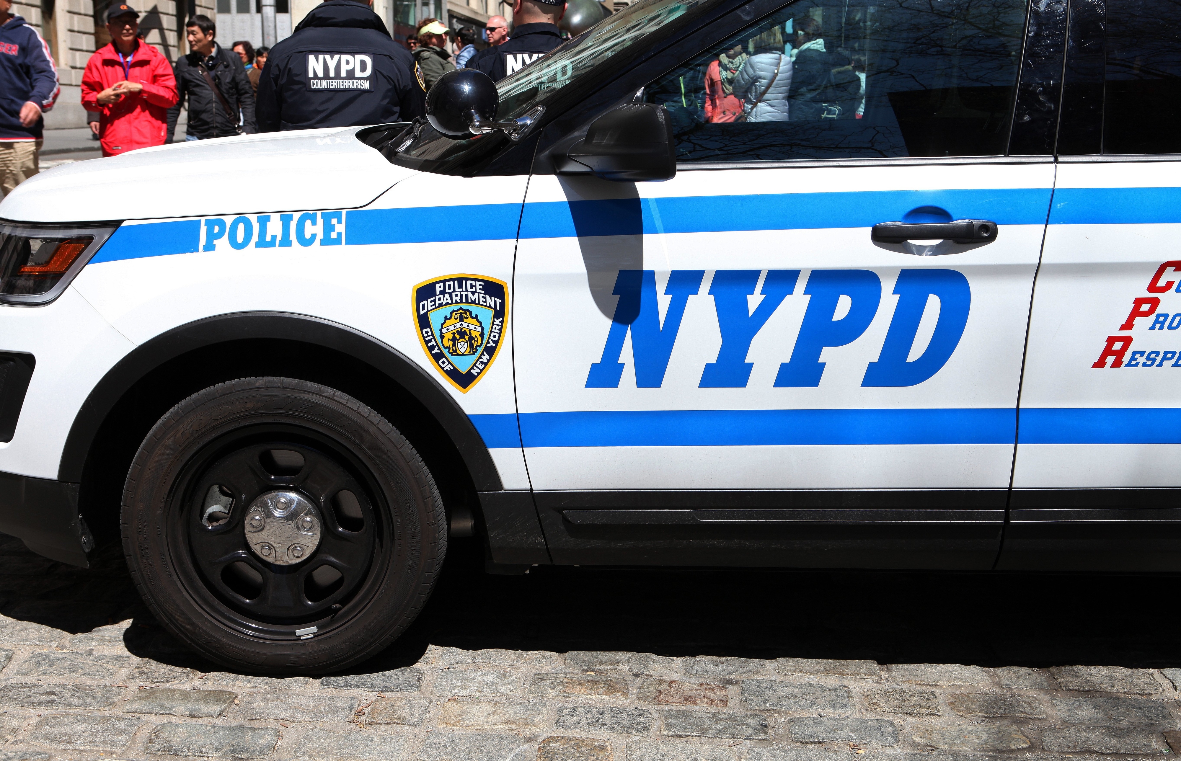 NYPD police vehicle on duty with a visible crowd in the background