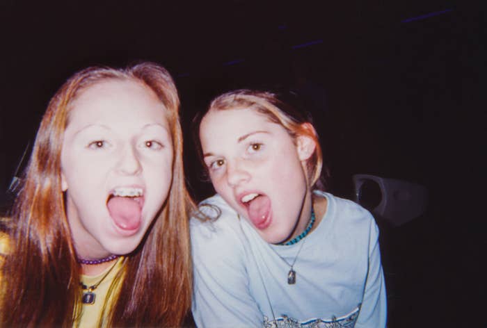 Two individuals sticking out tongues, wearing casual tops and beaded necklaces