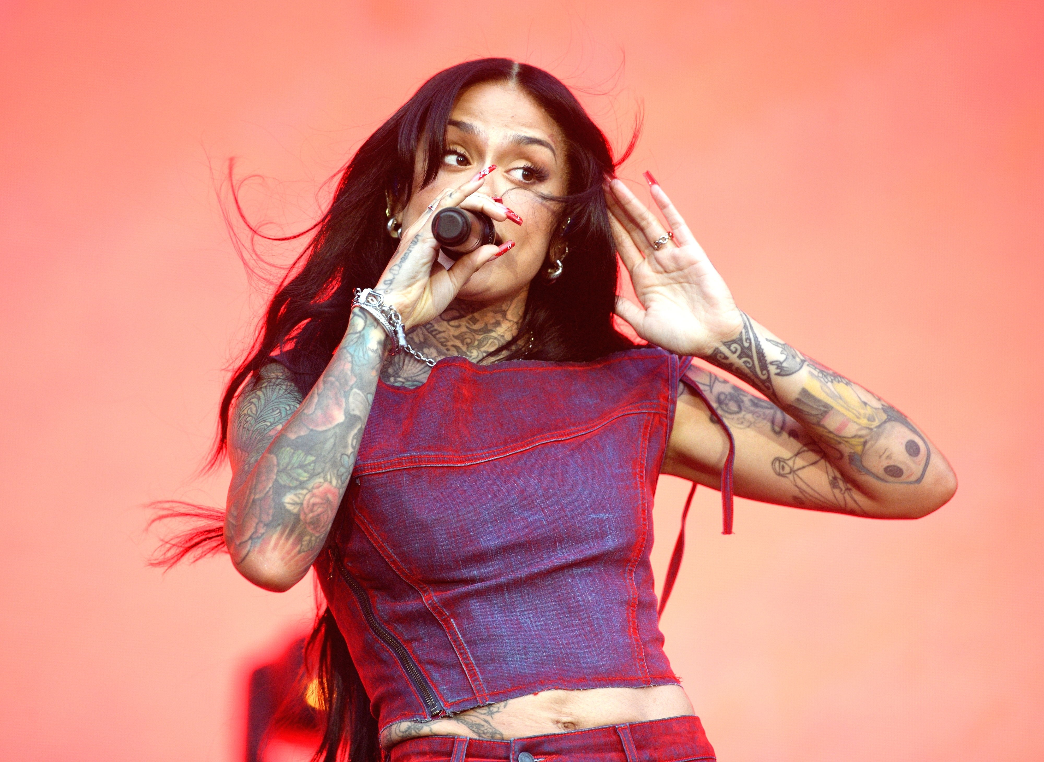 Kehlani performs onstage wearing a denim outfit, with a microphone in hand